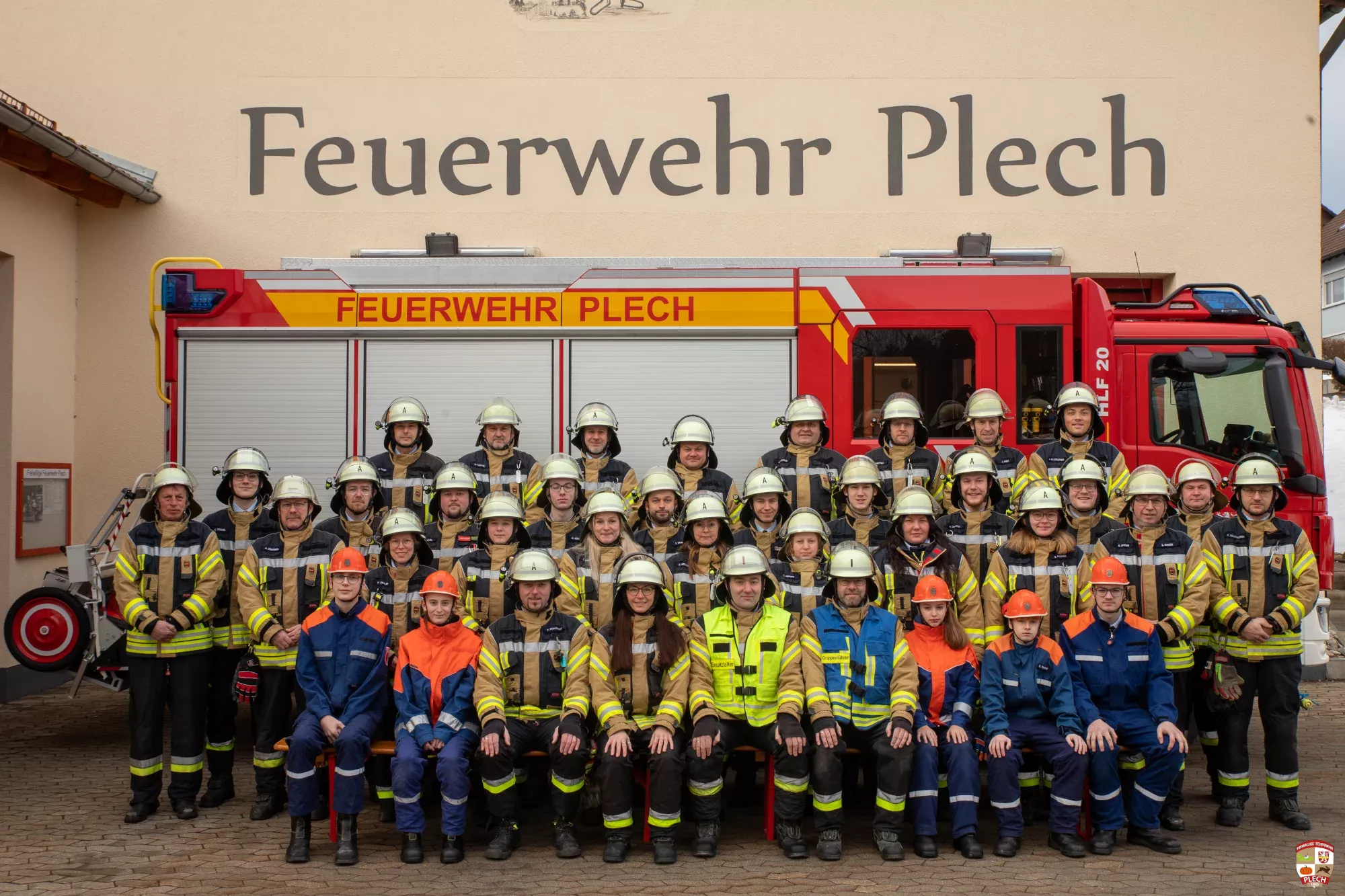 Mannschaftsfoto der Feuerwehr im Schutzanzug vor dem HLF 20